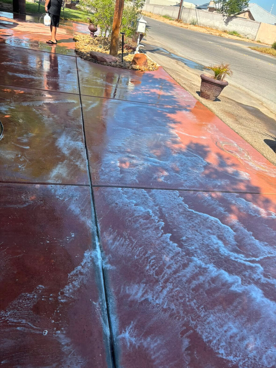 Red concrete being cleaned with soap during pressure washing